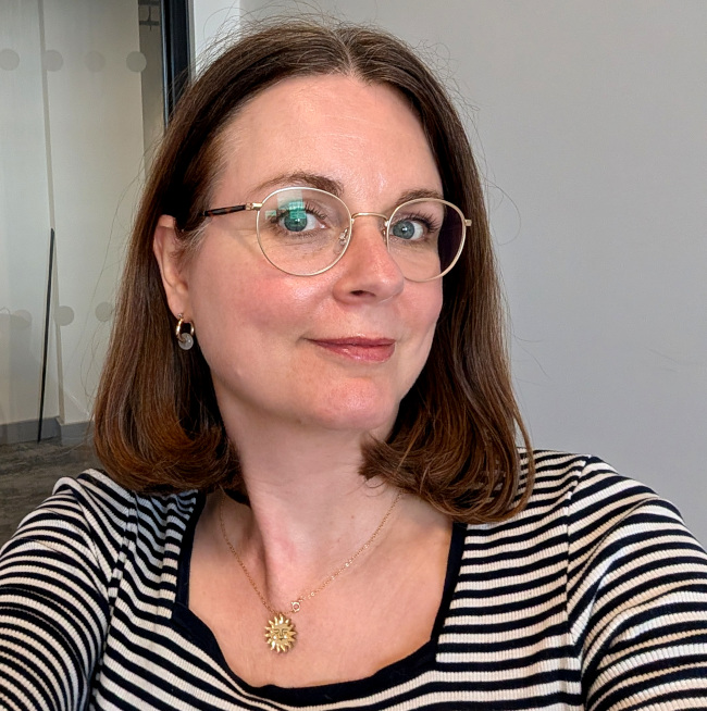 Sophie Keegan, TWiTCH Project Officer a white woman with brown hair wearing glasses and a striped top.